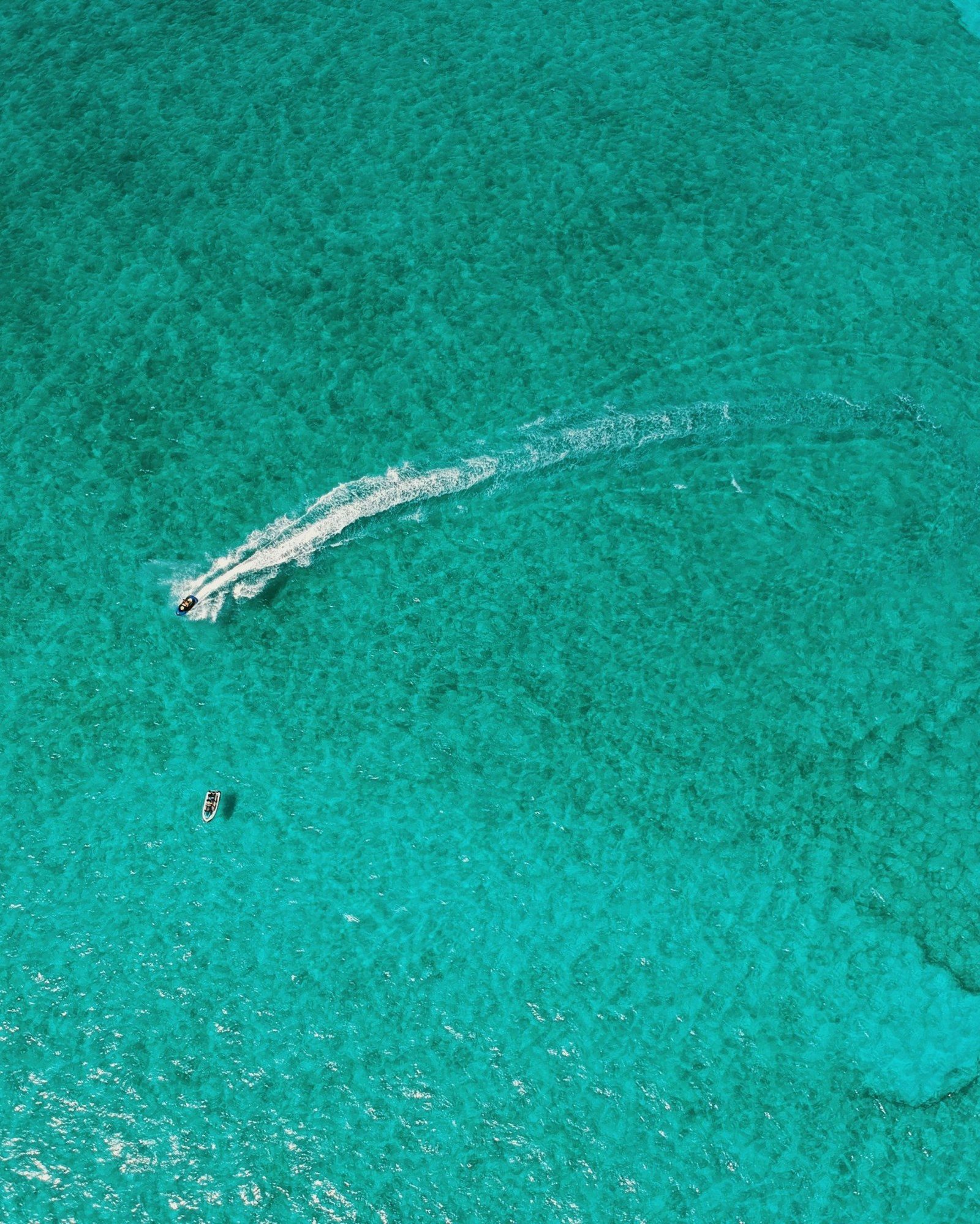 Mar Caribe turquesa visto desde el aire, con una moto acuática dejando su estela